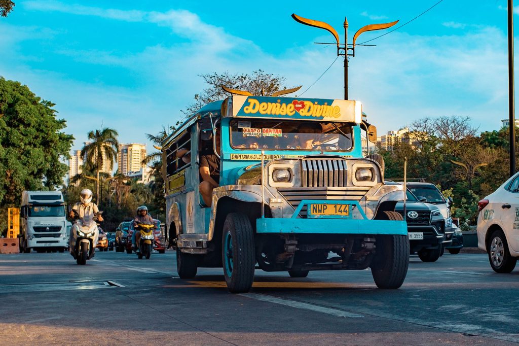 Iconic Filipino jeepney on a busy street in Manila during daylight.