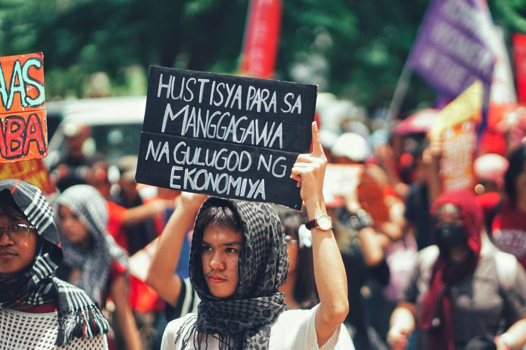 Protesters gathered outdoors holding signs demanding economic justice and workers' rights.