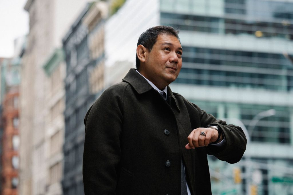 Respectable middle aged ethnic male entrepreneur in formal clothes checking time on wristwatch while waiting for meeting near